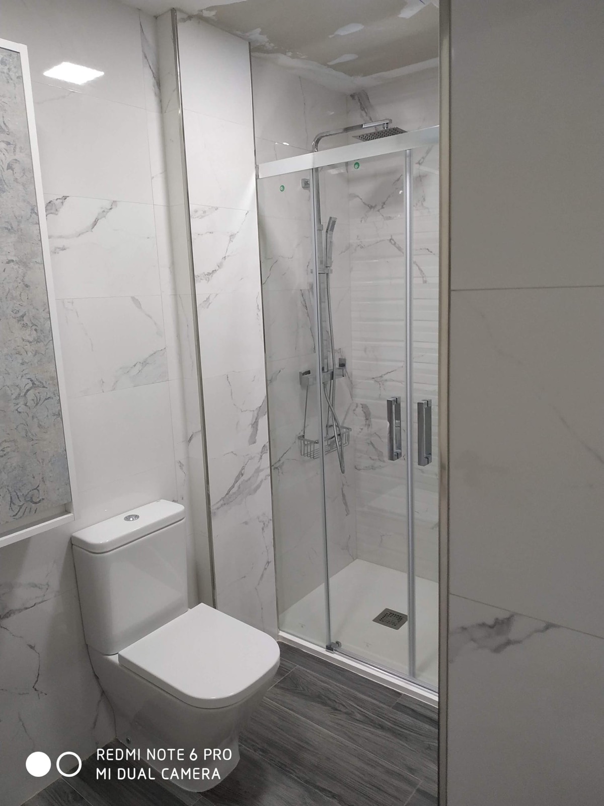 Baño — Baño con alicatado de mármol y ducha.